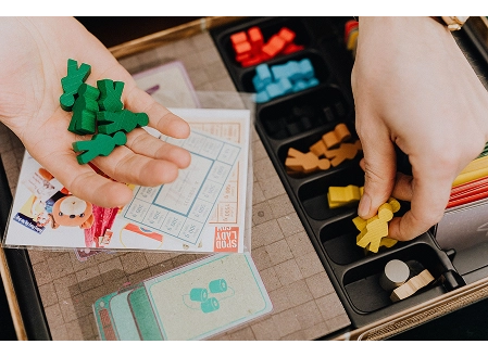 Hands sort green and yellow wooden pieces beside cards and other game components.
