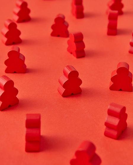 Multiple red wooden person-shaped pieces are arranged across a red surface.